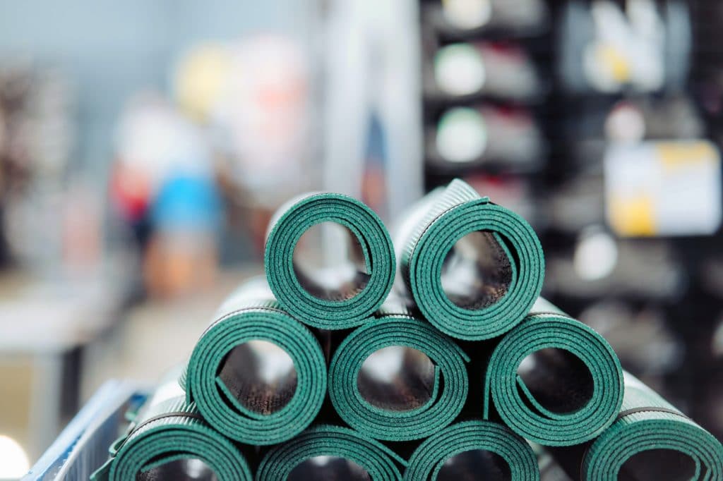 New rolled up yoga and fitness mats on a store shelf. Close view